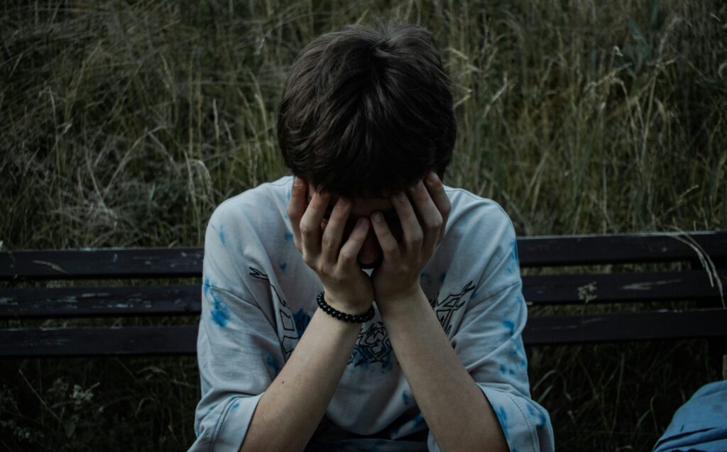 ベンチに座って顔に手を当てている男の子